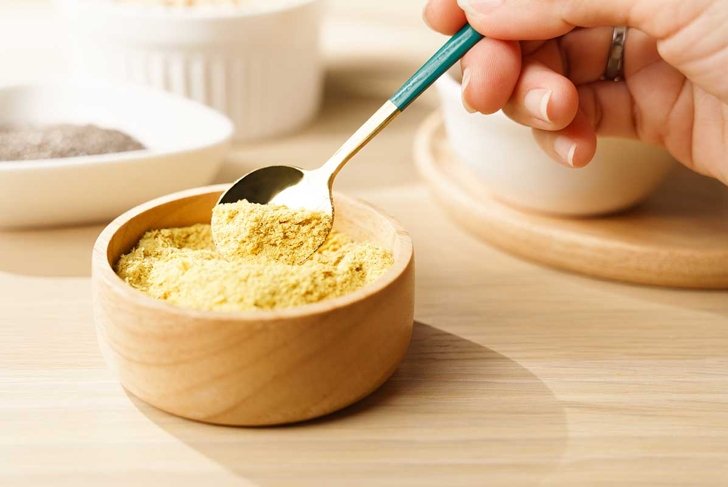 Nutritional yeast flakes in wooden bowl a great source of vitamins and minerals for vegan and plant-base diet contains amino acids, complete protein, Dairy free, Gluten free, Substitute, Superfoods.