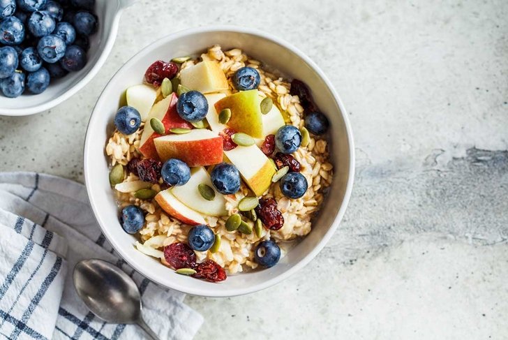 Bircher muesli or overnight oatmeal with apple, banana and blueberries in a gray bowl, copy space.