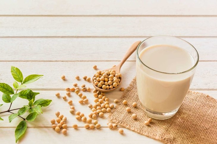 Soy milk in glass and soy bean on spoon it on white table background,healthy concept.